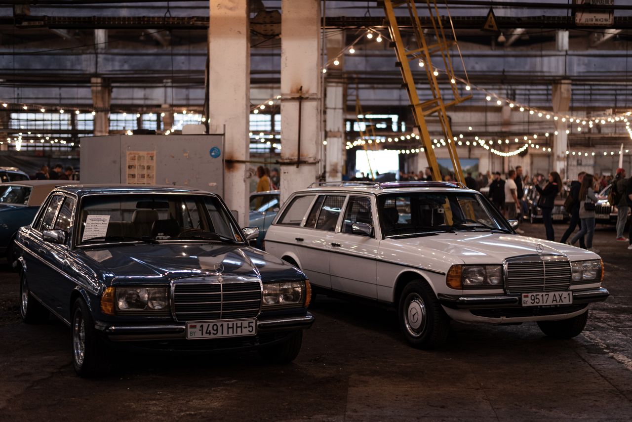 Classic Mercedes Benz sedans displayed at an indoor vintage car show with ambient lighting.